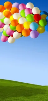 Colorful balloons float in a clear blue sky over a green hill.