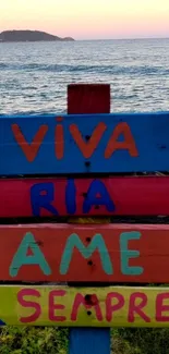 Colorful beach sign with ocean backdrop and inspiring text.