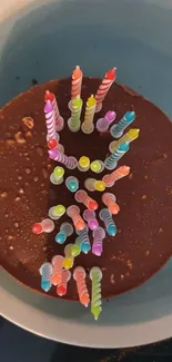 A chocolate cake with colorful birthday candles arranged on top.