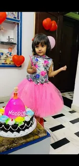 Child in pink dress at a birthday party with a colorful cake.