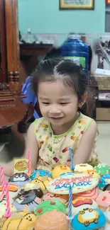 Smiling child with colorful birthday cupcakes and candles.