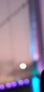 Silhouette of a bridge with twilight hues and colorful lights.