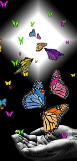 Artistic wallpaper with colorful butterflies on a black background and hands releasing them.