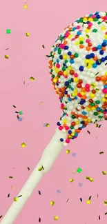 Colorful sprinkle-covered cake pop on a pink background.