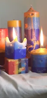 Colorful candles in various shapes on a soft beige cloth.