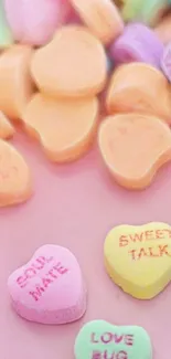 Colorful candy hearts on a pink background.