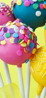 Colorful cake pops with sprinkles on a bright yellow background.