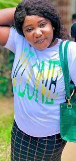 Woman in white t-shirt and plaid skirt with green handbag in a vibrant setting.