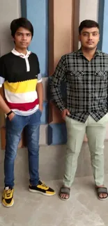 Two young men in stylish casual attire with colorful background.