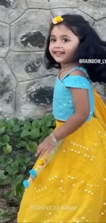 Joyful child in colorful attire against a stone wall.