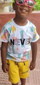 Child in a vibrant summer outfit with colorful patterns and sunglasses.