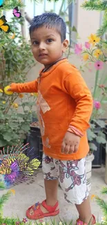 Child in orange shirt surrounded by colorful flowers and butterflies in a garden.