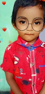 Cute child in red shirt with heart accents and large glasses.