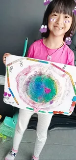 Child holding colorful painting with a cheerful smile.