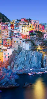 Vibrant coastal town at sunset with colorful buildings and a rocky seaside view.