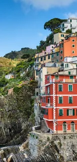 Vibrant wallpaper of colorful coastal town on rocky shoreline by the sea.