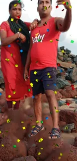 Couple at beach with colorful confetti and rocky background.