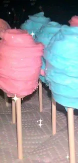 Pink and blue cotton candy pops on sticks in a vibrant setting.