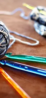 Colorful crochet hooks and yarn ball on a brown background.