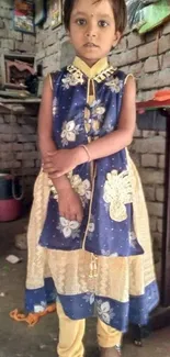 Child in colorful traditional attire against a rustic background.