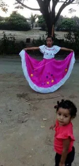 Young girl in pink dress performing a traditional dance outdoors.