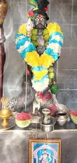 Colorful deity sculpture adorned with garlands in a temple setting.