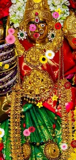 A deity adorned with gold jewelry and surrounded by vibrant flowers.