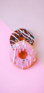 Pink and chocolate donuts with sprinkles on a pastel pink background.