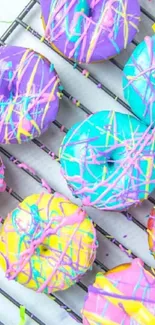 Colorful donuts with icing on a wire rack.