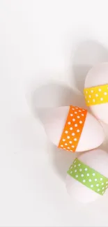 Colorful eggs with polka dot ribbons on a white background.