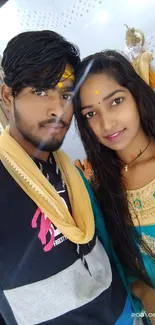 Couple in colorful ethnic attire posing indoors.