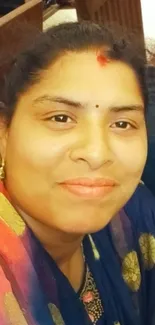 Portrait of a smiling woman in vibrant traditional attire.