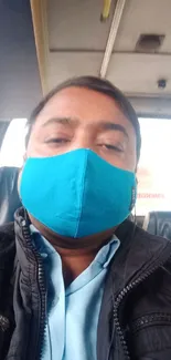 Person in blue face mask sitting on a bus, vibrant background.