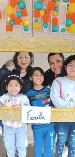 A family posing with colorful balloons and a golden frame.