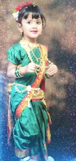 A young girl in green traditional attire posing cheerfully.