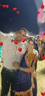 A festive couple at a night event with heart balloons.