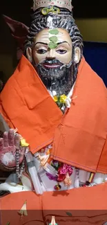 Vibrant figurine with orange cloth, adorned with flowers in a festive setting.