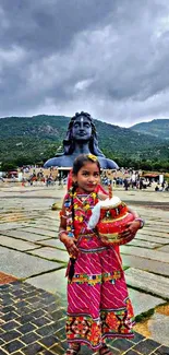 Child in colorful traditional attire with mountain in background.