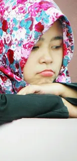 Woman in a colorful floral hijab, thoughtful expression.