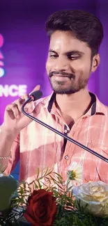 Young man speaking with floral decor and purple background.