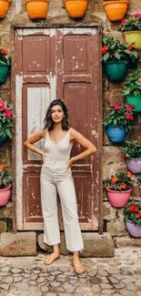 Woman standing by colorful wall of flower pots.