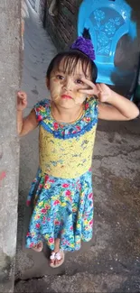 Young girl in colorful floral dress with a purple accessory.