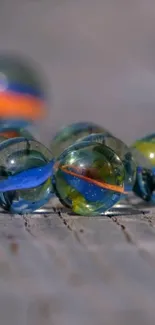 Colorful glass marbles on a wooden surface.