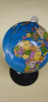 Colorful globe depicting continents on a beige background.