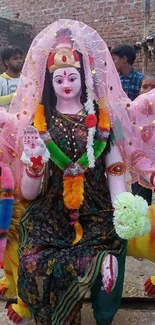 Colorful goddess idol with festive decorations in outdoor setting.