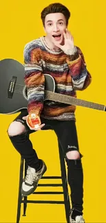 Young person with guitar on a stool against a bright yellow background.