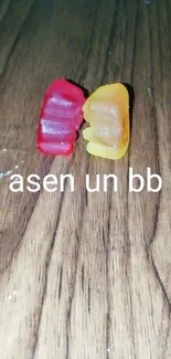 Two gummy bears on wooden surface.