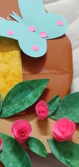 Handmade paper art with green leaves, a blue butterfly, and pink roses.