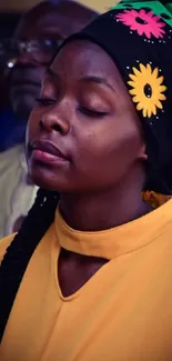 Vibrant image of a person with a floral headscarf and a yellow dress.