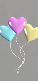 Three colorful heart-shaped balloons on a gray background.